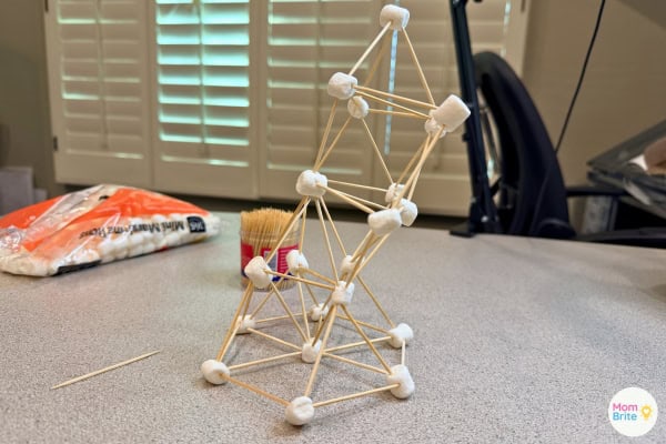 Adult marshmallow and toothpick tower about to fall over