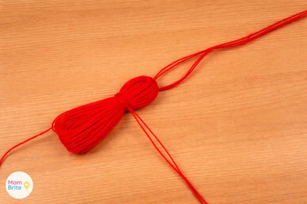 Bundle tied to form tassel head] Alt text: Red yarn tied below the top to form the head of the tassel