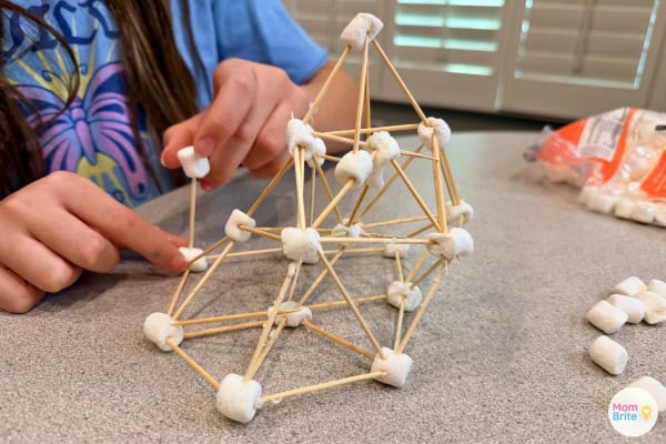 Kid building marshmallow tower, mid-construction