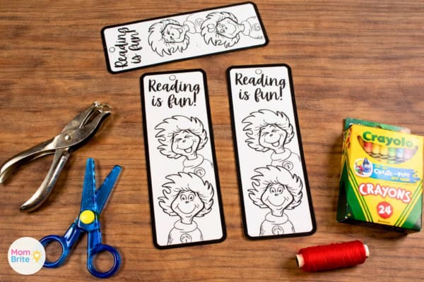 Supplies for Thing 1 and Thing 2 printable bookmarks including template, scissors, hole punch, crayons, and red yarn
