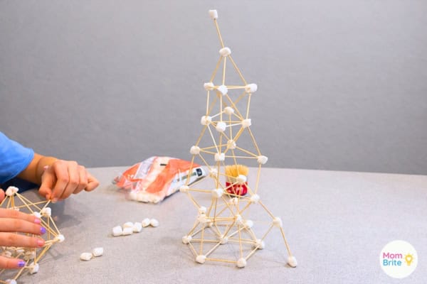 A finished marshmallow toothpick tower and a child building one