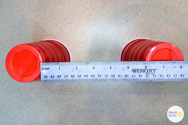 Two Solo cups set up as supports for marshmallow bridge building challenge with a ruler showing 6 inches gap