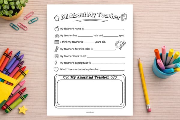 All About My Teacher printable worksheet mockup on a light wood desk with crayons, pencil, and markers